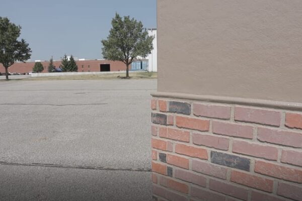 The corner of a Polar King walk -n freezer with a half-brick exterior painted brown standing outside with trees in the back